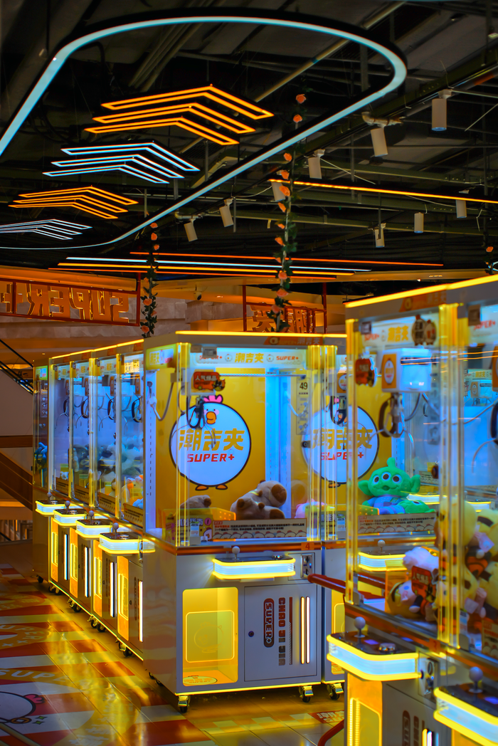 services-03 Colorful arcade claw machines in an indoor setting with plush toys and neon lights.