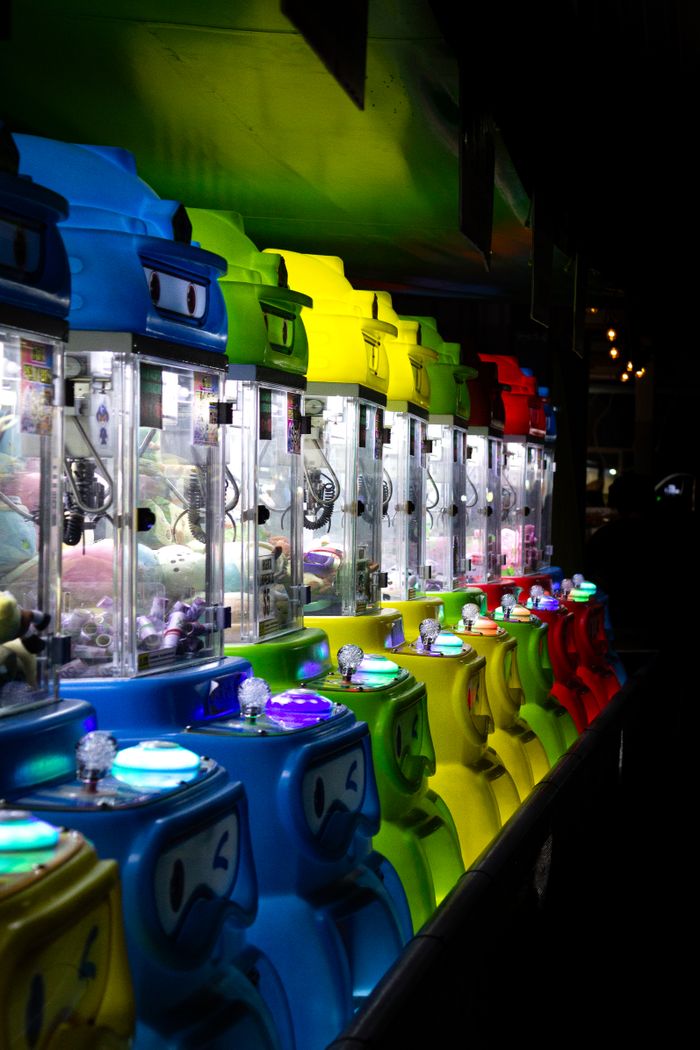 services-02 Colorful arcade claw machines illuminated at night, creating a fun and lively atmosphere.