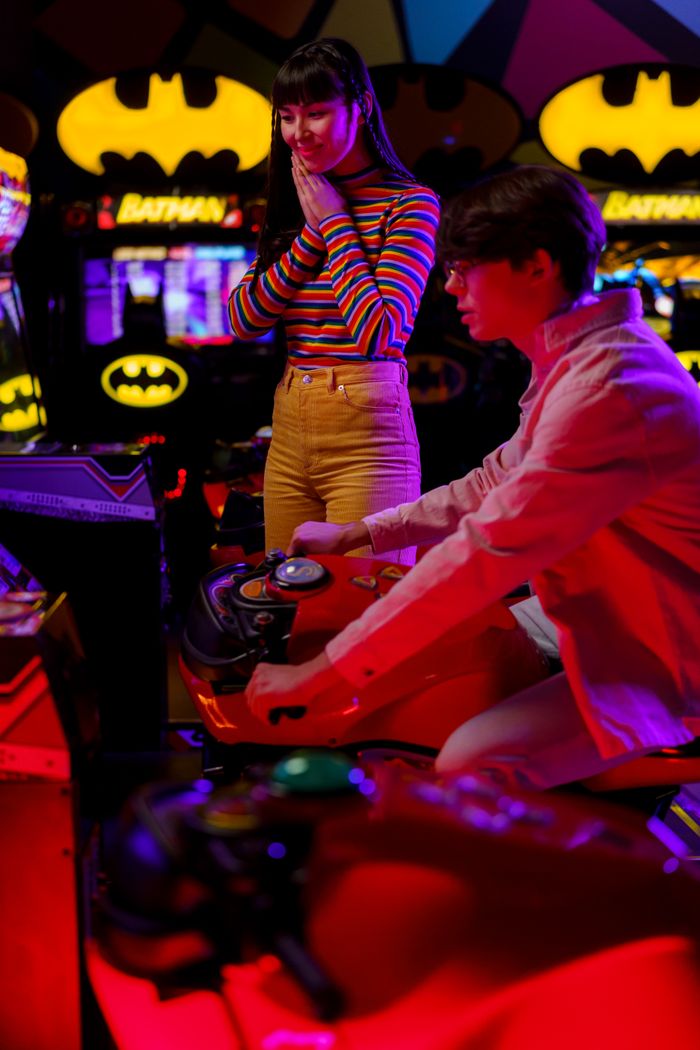 about-us-02 A couple playing a motorcycle racing video game at an amusement arcade.