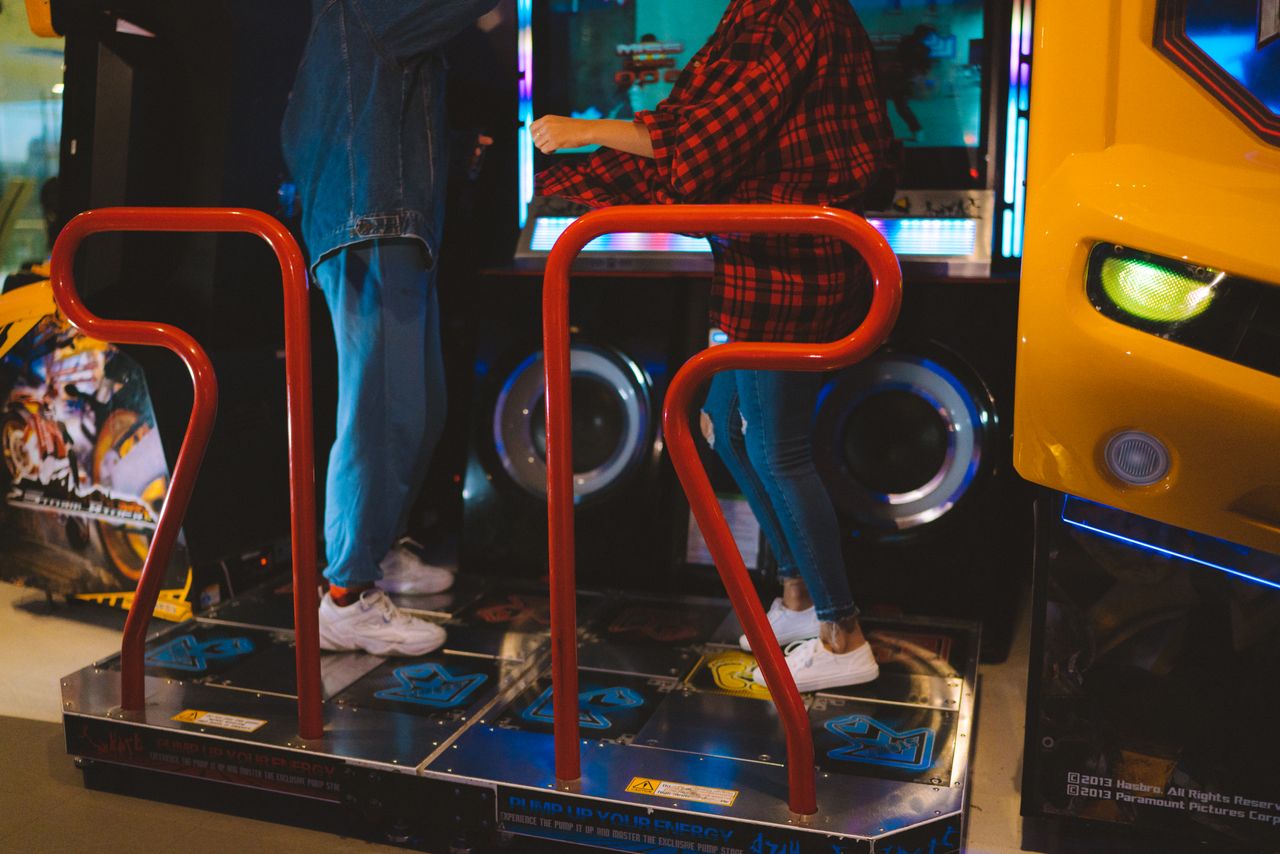 services-04 Adults having fun on a dance arcade game indoors. Vibrant, recreational, gaming fun.